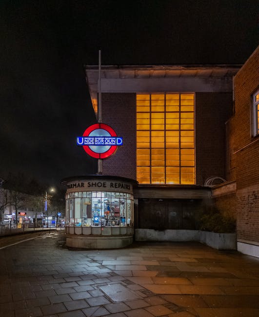 A view of Colliers Wood tube station platform during daytime, showing multiple sets of railway tracks curving into the distance. The platform edge features tactile paving and a yellow safety line, wit
